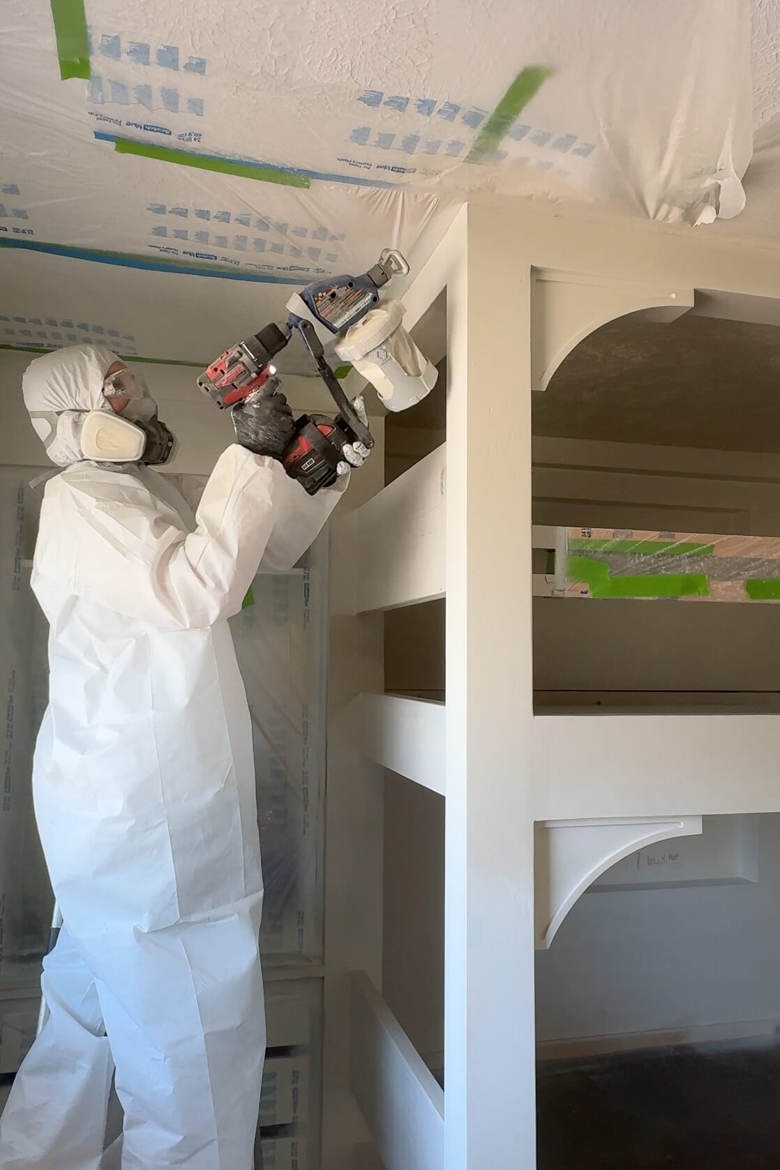 Painting DIY bunk beds with a sprayer.